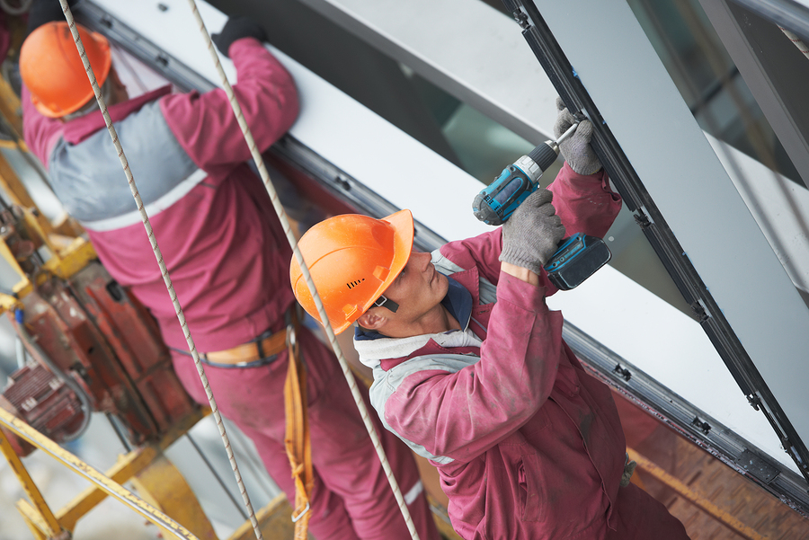 Two builders worker installing glass windows on facade of busine